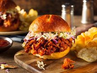 Ein Hamburger mit Jackfrucht liegt auf einem Holzbrett.