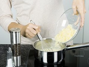 eine Person rührt den Käse in die Soße.