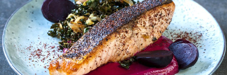 Rote Bete mit Kartoffelpüree und Fisch auf einem Teller.