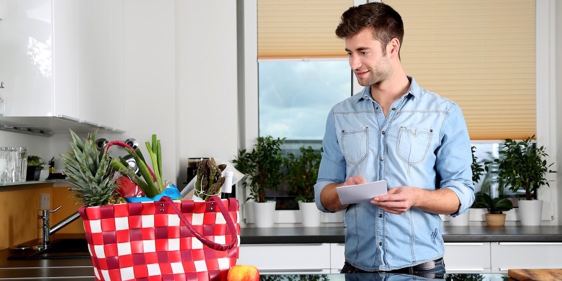 Ein Mann steht mit seinen Einkäufen in der Küche.. Artikel "Lagerung" öffnen.