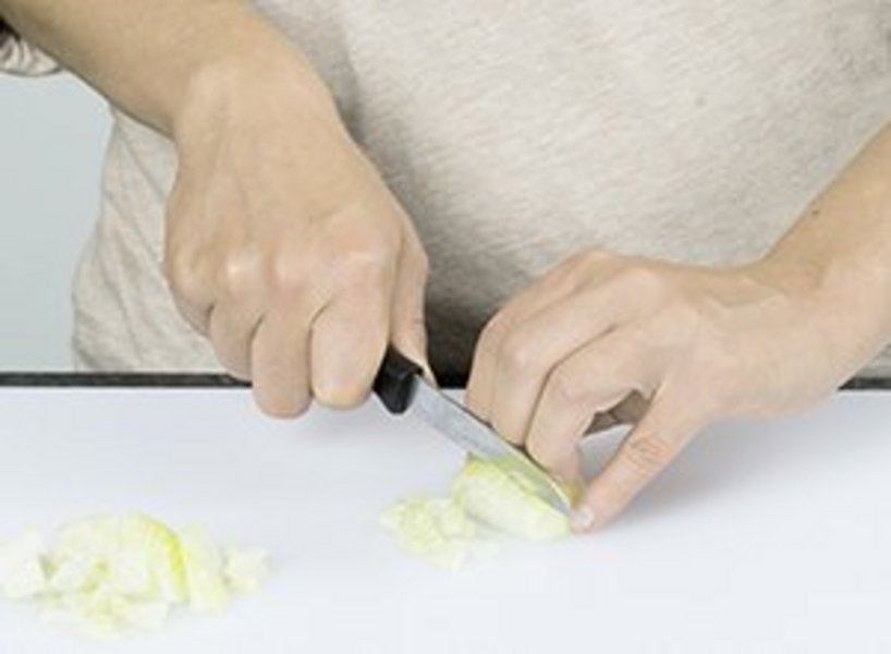 Person schneidet eine Zwiebel in kleine Würfel.