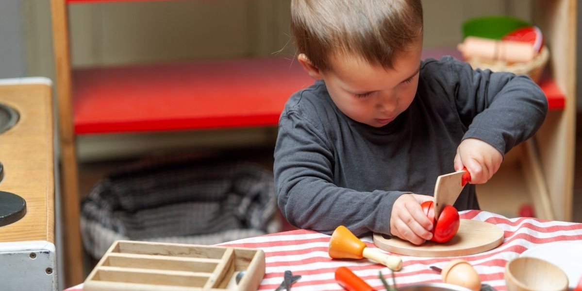 Ein Junge spielt mit Holzmesser und Holzgemüse.. Artikel "Ernährungsbildung in der Kita" öffnen.
