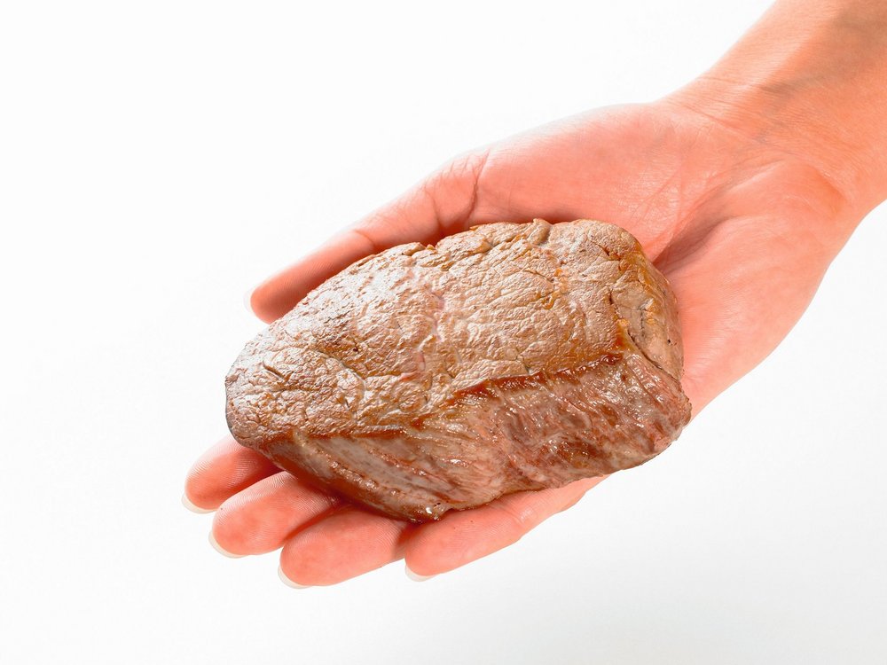 Eine Hand hält ein Stück Fleisch.