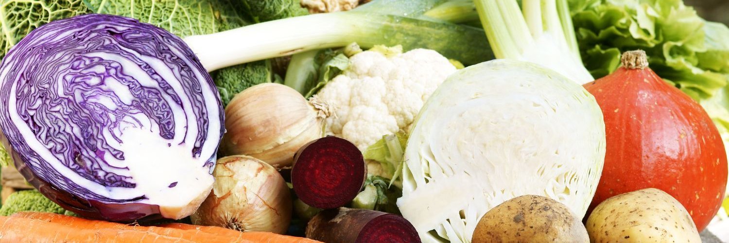 Auf einem Tisch liegen halbierter Rot- und Weißkohl, Hokkaido, Möhren, rote Bete, Blumenkohl, Kartoffeln, Lauch, Wirsing, Salat und Zwiebeln.