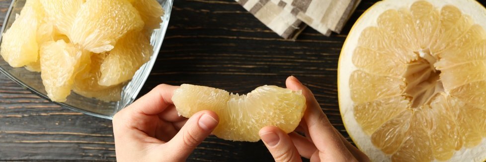 Jemand macht eine Pomelo in kleine Stücke.