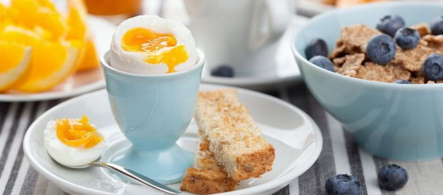 Aufgeschlagenes Ei auf Teller mit Brotstreifen