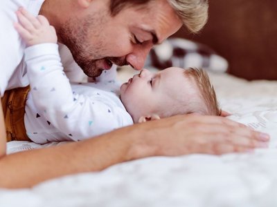 Ein Vater kuschelt mit seinem Baby Nase an Nase.