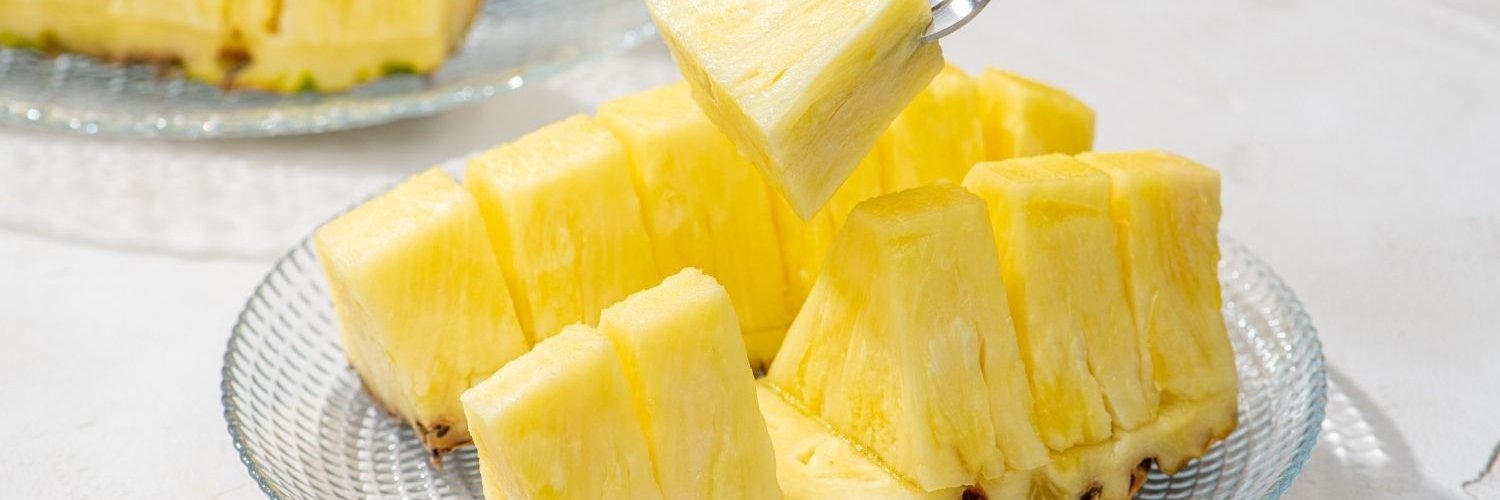 Ananasstücke liegen auf einem Glasteller.