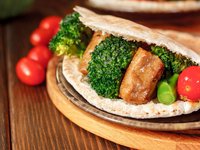 Eine Brottasche mit Seitanpattie und Gemüse ist abgebildet.