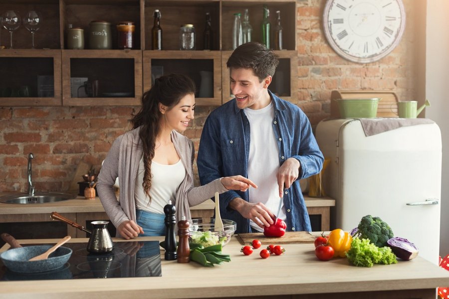 Eine junge Frau und ein junger Mann kochen zusammen am Küchentresen.