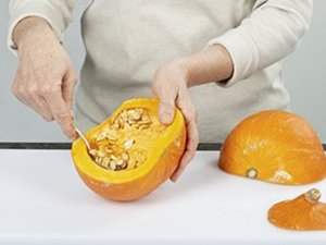 Eine Person kratzt mit einem Löffel die Fasern und Kerne aus.