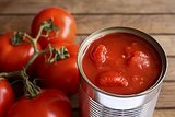 Geöffnete Dose mit Tomatenstücken und ganzen Tomaten daneben