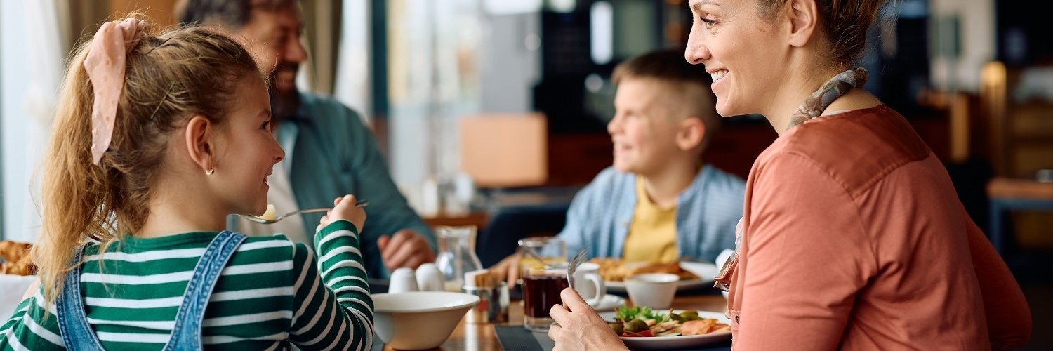 Eine Familie sitzt in einem Restaurant gemeinsam am Tisch und isst. 