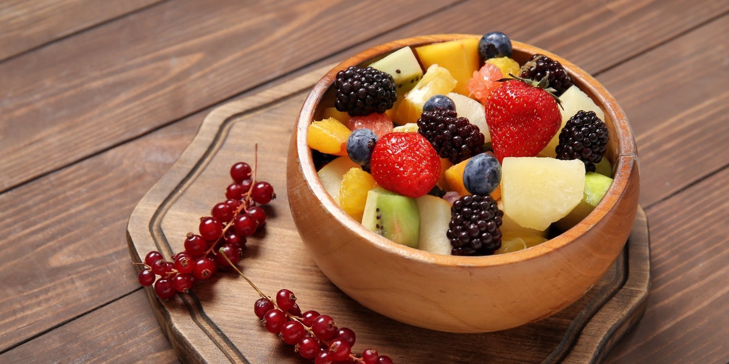 Ein bunter Obstsalat mit Erdbeeren, Brombeeren, Heidelbeeren, Apfel und Johannisbeeren in einer Holzschüssel. . Artikel "Bunte Früchte für den Obstsalat" öffnen.