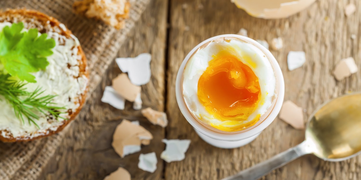 Waxhsweich gekochtes Ei steht geöffnet inn einem Eierbecher auf einem Holztisch.. Artikel "Eier: Gesundheit und Umwelt" öffnen.