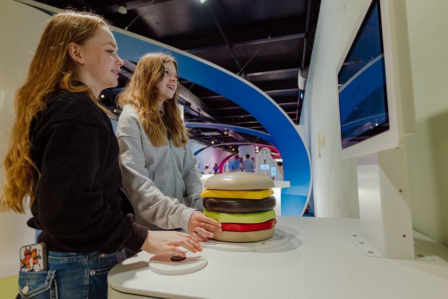 Zwei Jugendliche stehen an einem Ausstellungsexponat, der einen Hamburger darstellt.