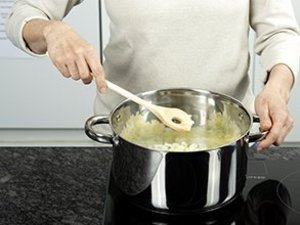 Eine Person kocht mit einem großen Topf.