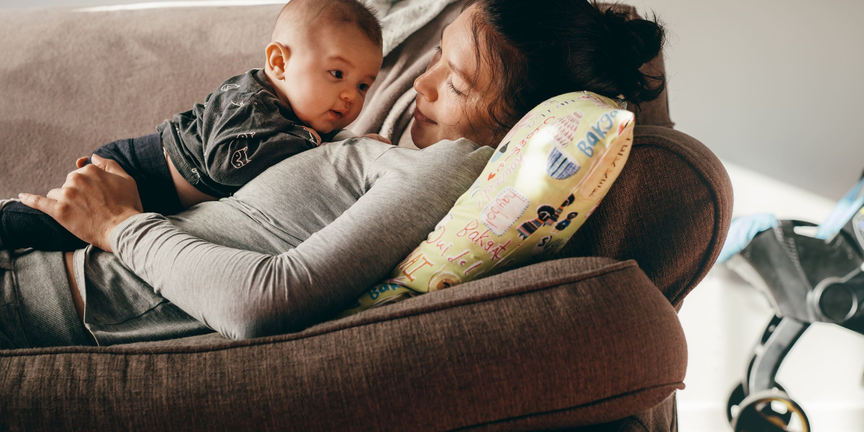 Eine Mutter und Ihr Baby liegen auf der Couch und kuscheln.. Artikel "Essen im ersten Lebensjahr" öffnen.