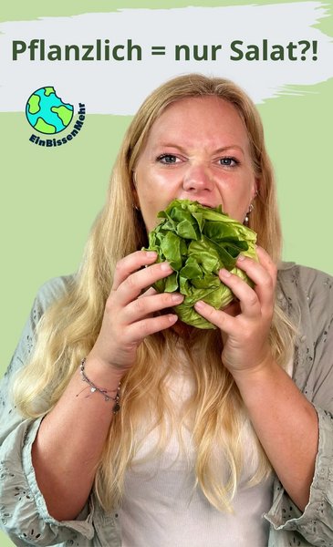 Eine blonde junge Frau beißt in einen ganzen Kopfsalat.