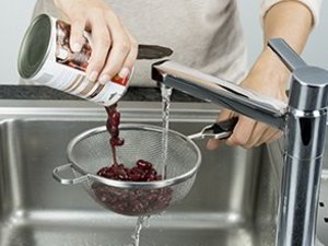 Eine Person tropft Kidneybohnen im Sieb ab.