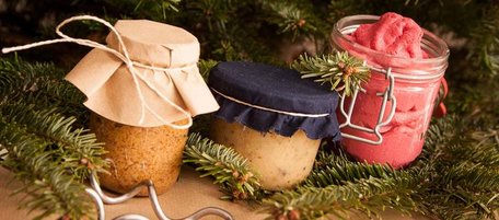 Drei Gläser mit selbstgemachten Weihnachtsgeschenken aus der Küche: Senf, Bratapfel-Marmelade und rote Knete.