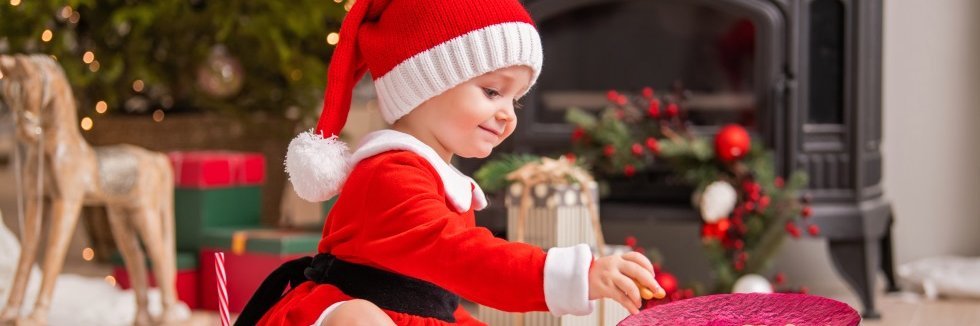 Kleines Kind mit roter Weihnachtsmütze greift nach Plätzchen.