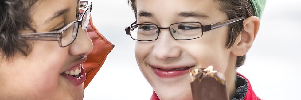 Zwei Jungen mit einem Schokoladeneis lachen sich an.