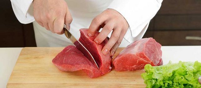 Koch schneidet Scheibe von Rindfleischstück ab