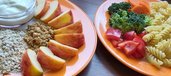 Zwei Teller mit Obst und Haferflocken, Gemüse und Nudeln