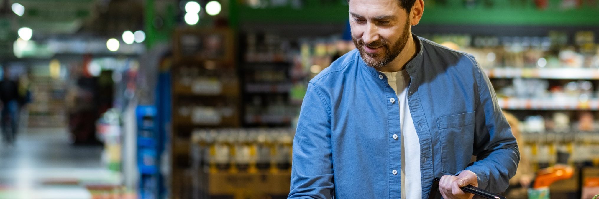 Ein Mann sucht Gemüse an der Gemüsetheke im Supermarkt aus. 