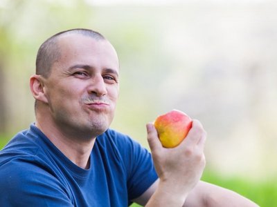 Ein Mann isst genüsslich einen Apfel.