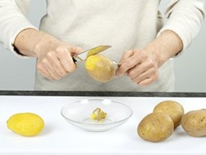 eine Person pellt die Kartoffeln.