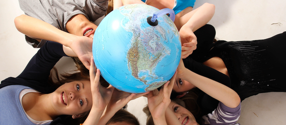 Ein Gruppe Jugendlicher liegt im Kreis auf dem Boden und hält einen Globus in den Händen 