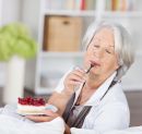Ältere Frau genießt ein Stück Obstkuchen