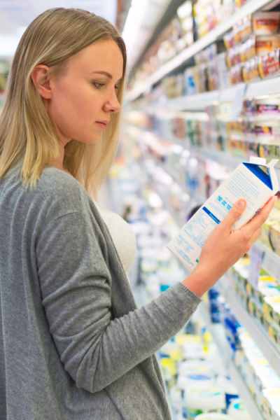 Frau checkt Etikett von Milchflasche