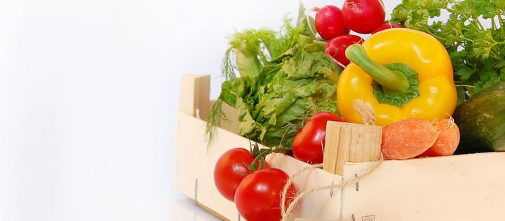 Holzkiste mit frischem Gemüse, unter anderem Tomaten, Paprika, Karotten, Radieschen und Salat