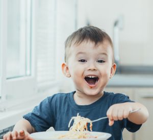 Junge isst lachend Spaghetti