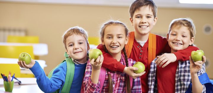 lachende Schulkinder inder mit Äpfeln in der Hand