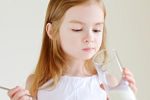 Mädchen schaut skeptisch ins Milchglas