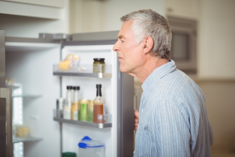 Mann schaut in Kühlschrank
