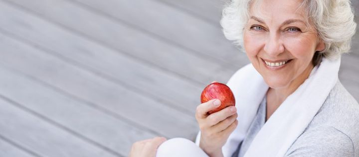 Seniorin mit rotem Apfel in der Hand