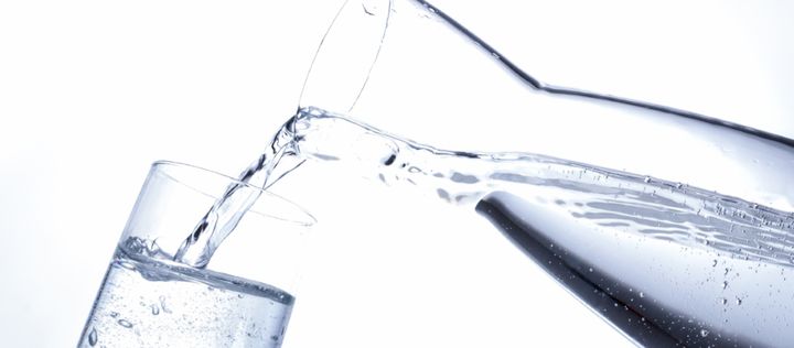 Sprudelwasser wird aus einer Karaffe in ein Glas gegossen