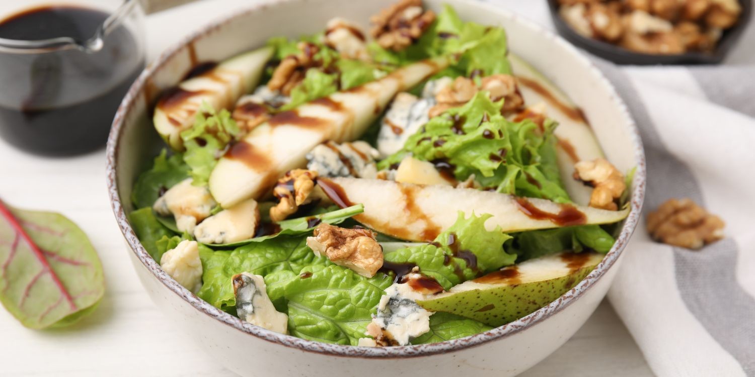 Eine Salatschüssel mit grünem Salat, Birnen, Walnüssen und Balsamico-Dressing. . Artikel "Birnen herzhaft genießen" öffnen.