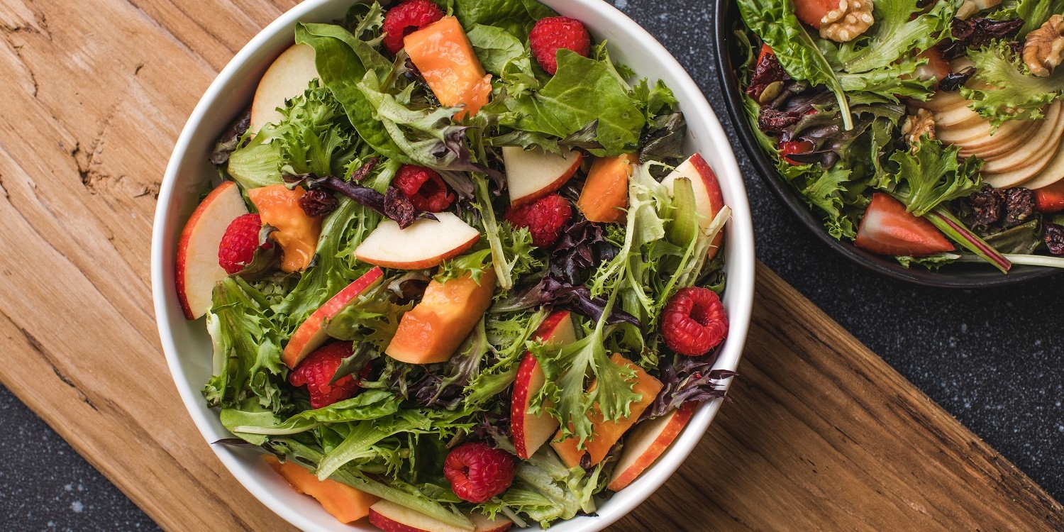 Auf einem weißen Teller ist ein Salat aus Rucola, Apfelstücken, Himbeeren und gebackenen Käsenuggets angerichtet.. Artikel "Jetzt startet die Himbeerzeit" öffnen.