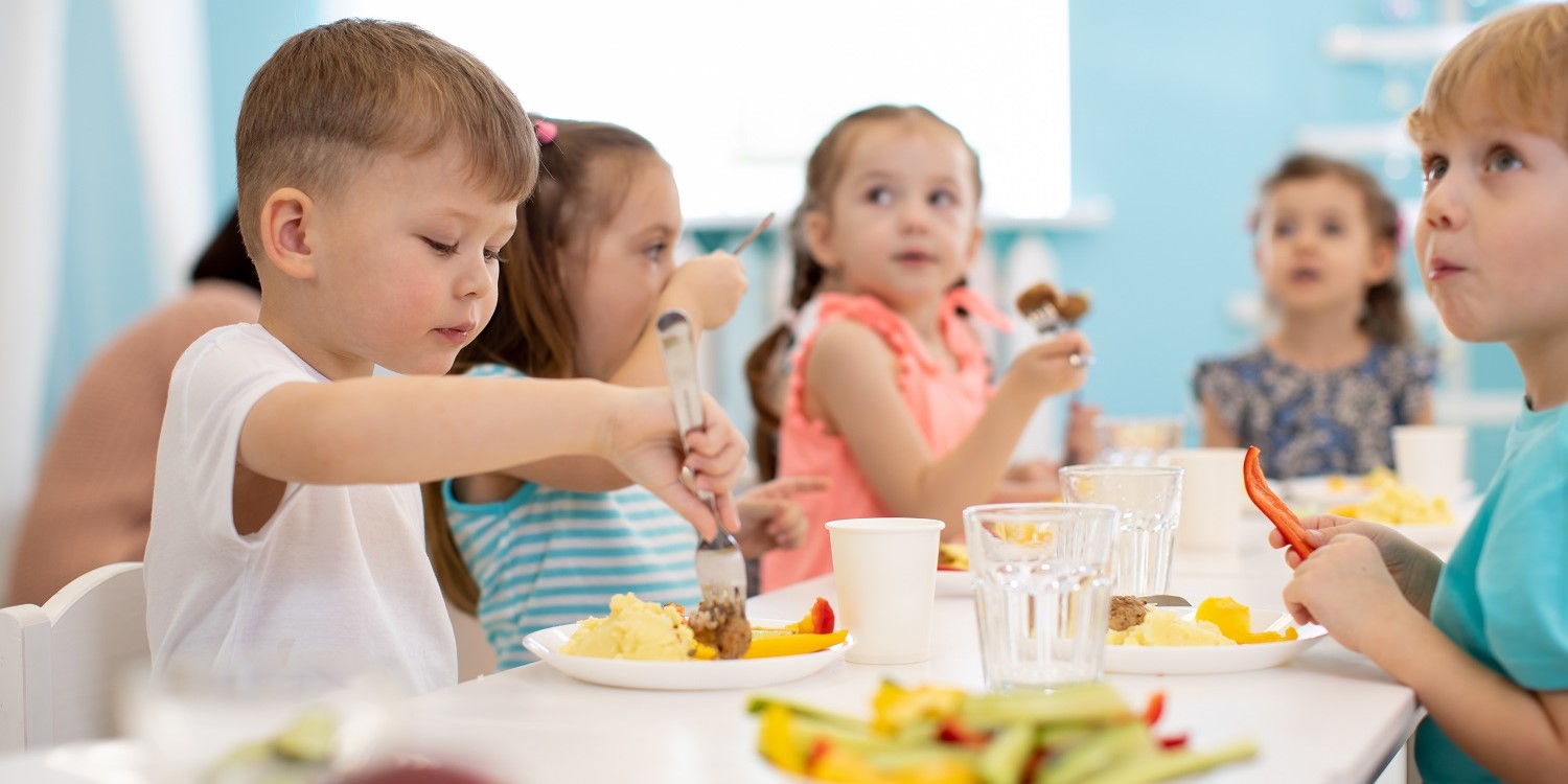 Eine Gruppe von Kindergartenkindern sitzt am Tisch und isst gemeinsam. . Artikel "„Heute hat’s wieder richtig gut geschmeckt!“" öffnen.
