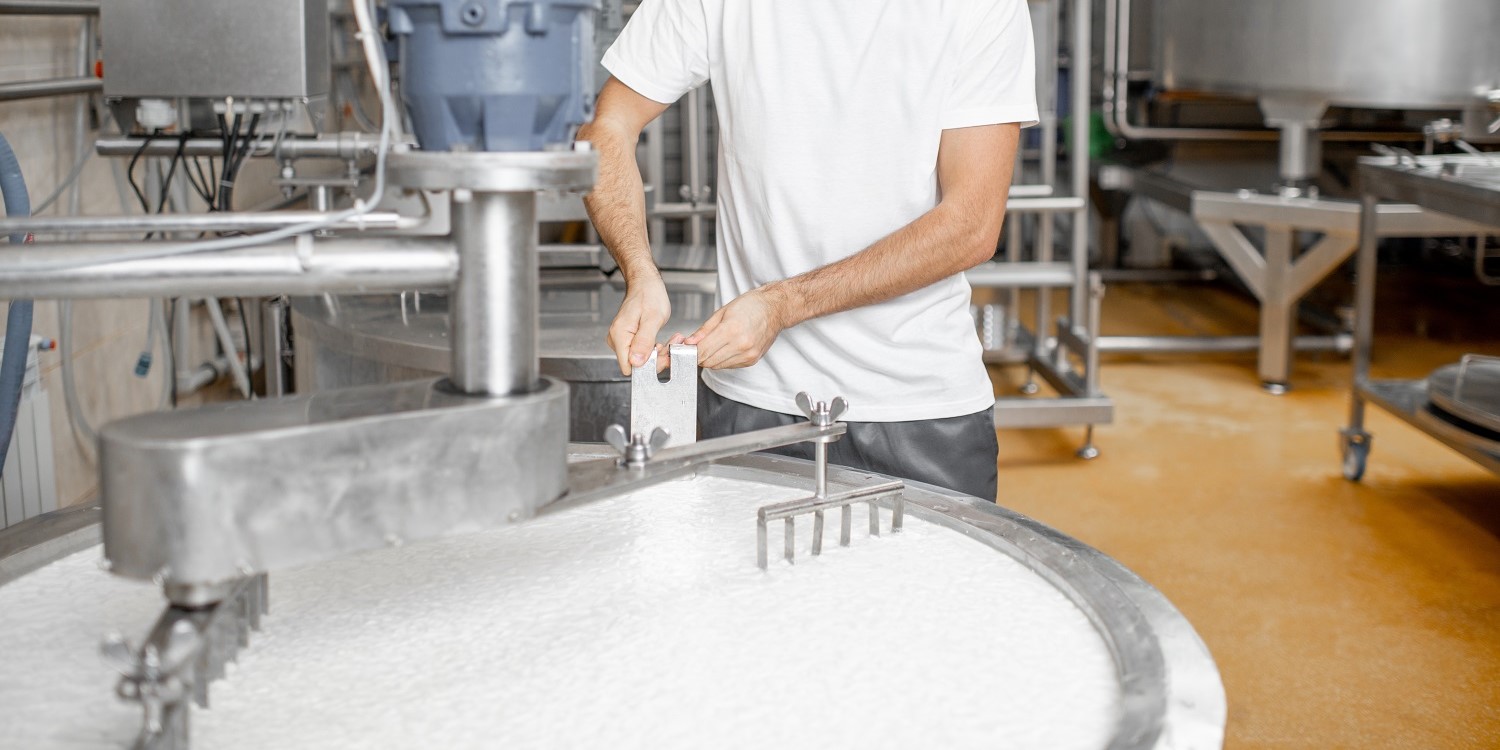 Ein Mann mischt Milch im Edelstahltank während des Fermentationsprozesses bei der Käseherstellung. Artikel "Zukunft der Ernährung aktiv mitgestalten" öffnen.