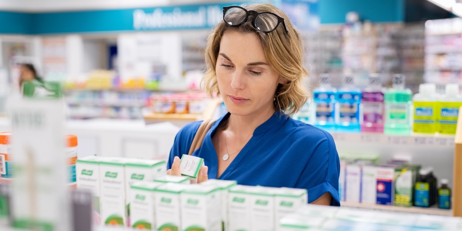 Eine Frau steht vor einem Regal mit Nahrungsergänzungsmitteln und liest die Beschriftung auf der Verpackung.. Artikel "Power für das Immunsystem?" öffnen.