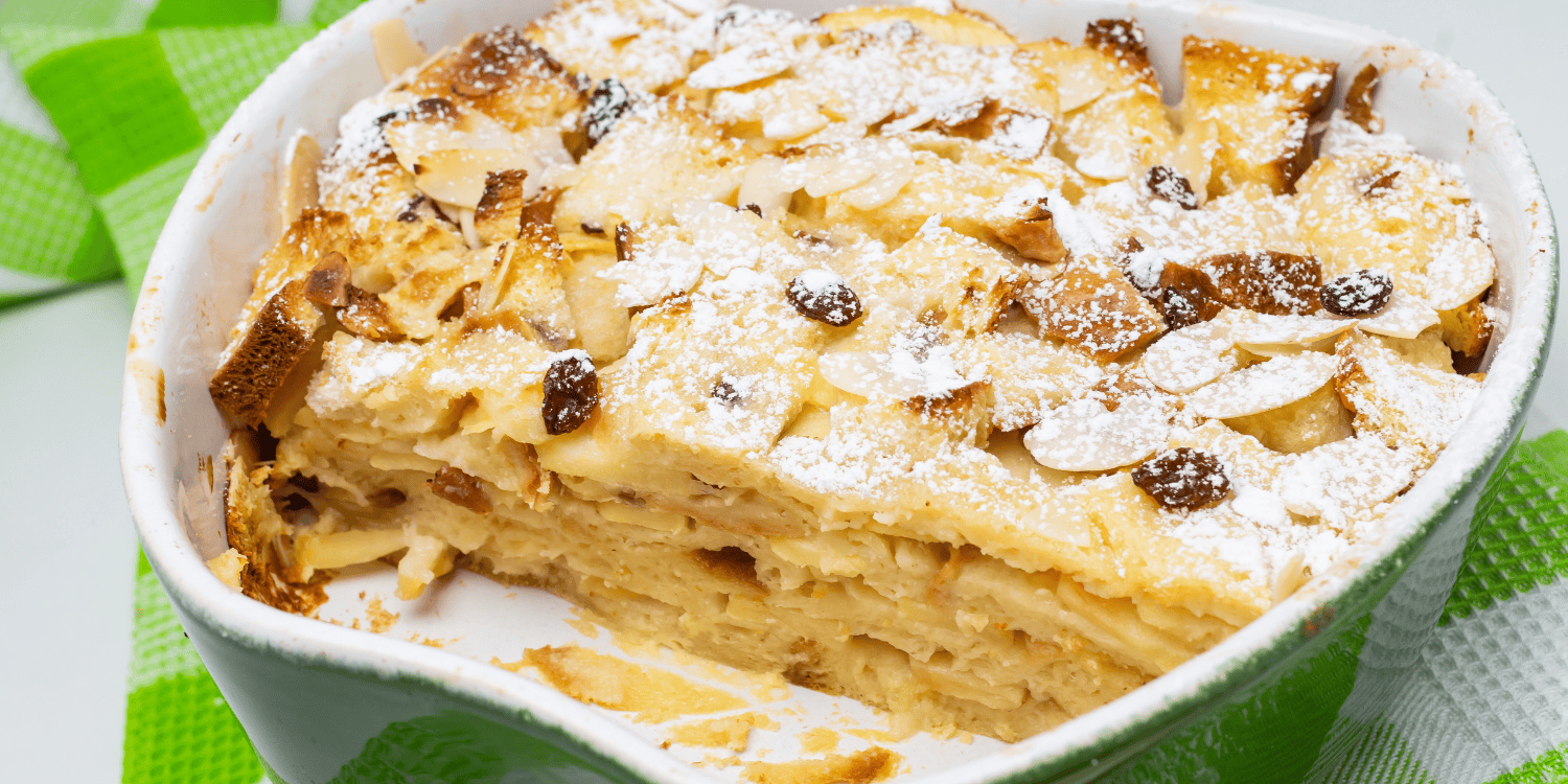 In einer grünen Ofenform ist ein Brotauflauf mit Mandeln, Rosinen und Puderzucker, der auf einer grün-weiß karierten Serviette steht. . Artikel "Die besten Brotretter-Rezepte" öffnen.