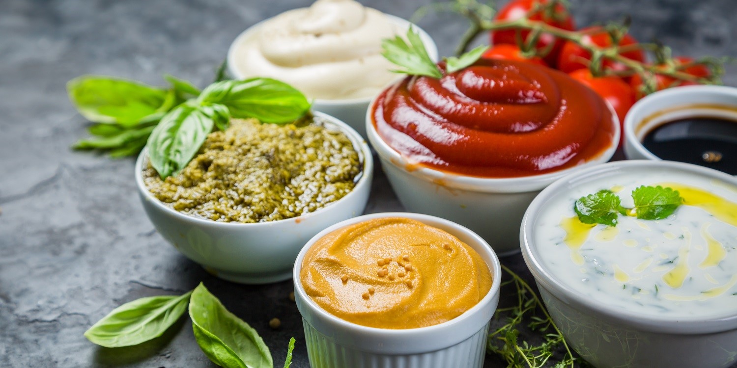 Verschiedene Soßen und Dips in kleinen weißen Schälchen stehen auf einem Tisch.. Artikel "Soßen und Dips zum Grillen " öffnen.