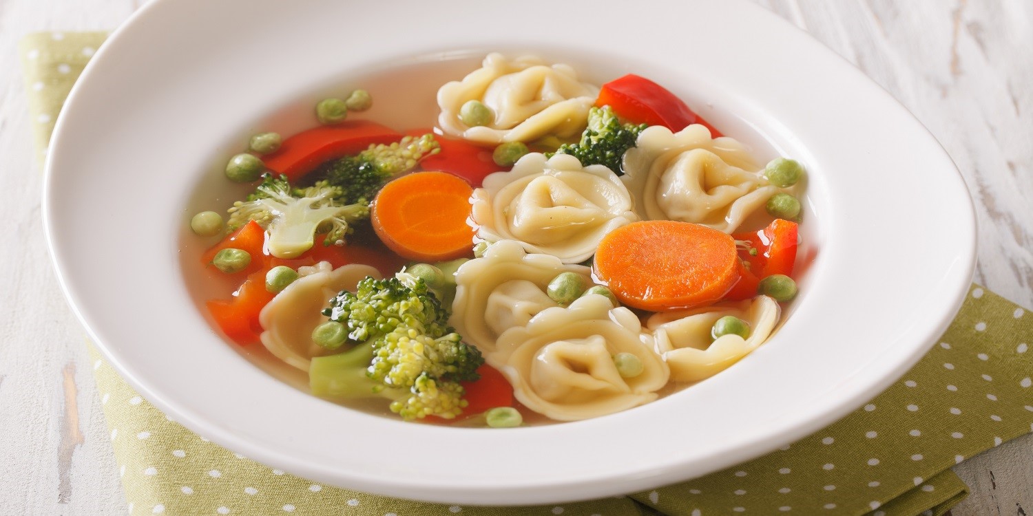 In einem weißen Suppenteller befindet sich eine Suppe mit Tortellini, Brokkoli, Erbsen, Karotten und Paprika. . Artikel "Frisch trifft fertig" öffnen.